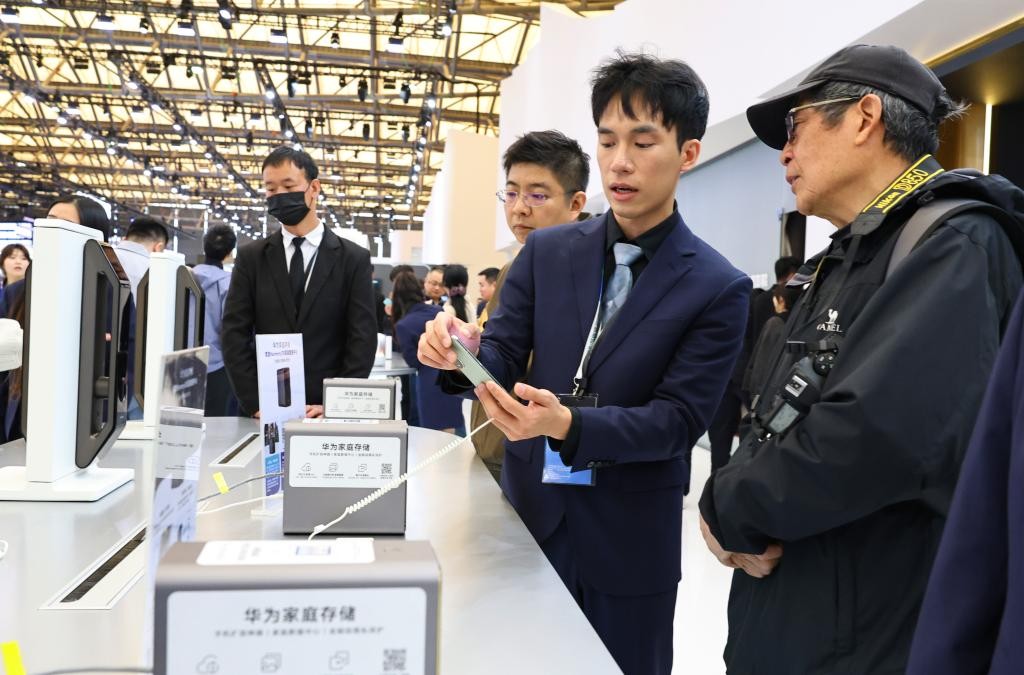 3月20日，工作人员（右二）在向参观者介绍一个家庭数据中心存储设备。当日，2025中国家电及消费电子博览会（AWE2025）在上海新国际博览中心开幕。（新华社记者 方喆 摄）