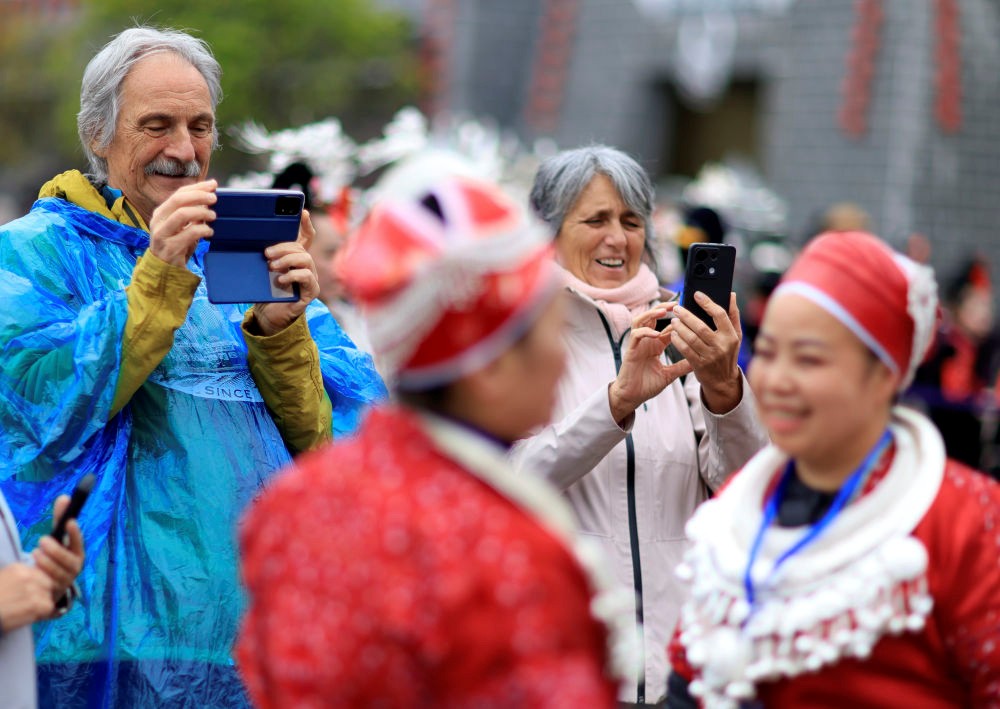 4月12日，外国游客在贵州省黔东南苗族侗族自治州台江县举行的“苗族姊妹节”庆祝活动上拍摄。新华社记者刘续 摄