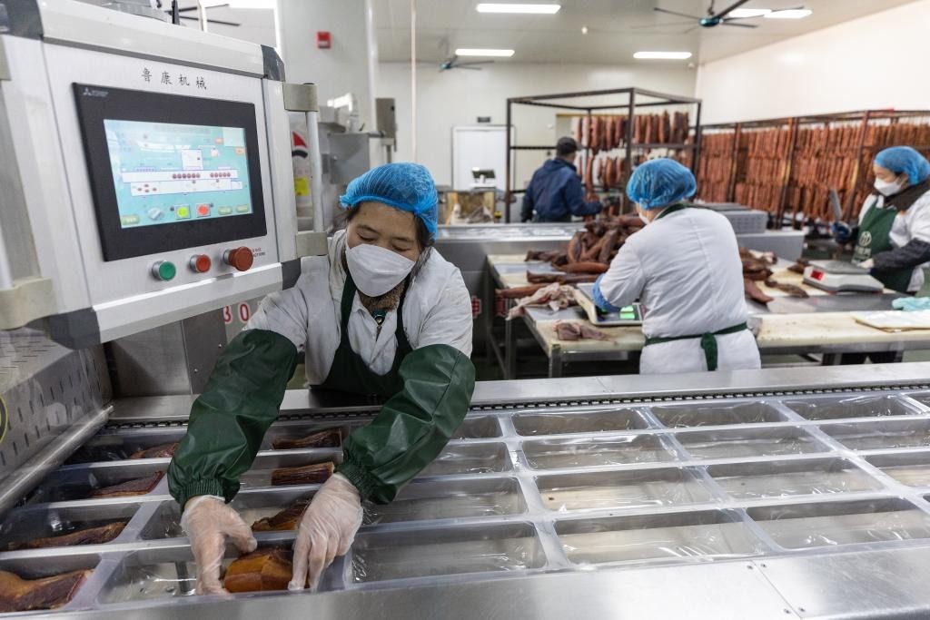 1月20日，在重庆市城口县坪坝镇新华村重庆美缀美食品有限公司，工人在外包装车间利用自动打包机封装腊肉。城口老腊肉是地处大巴山腹地的重庆市城口县国家地理标志产品。新华社记者黄伟 摄