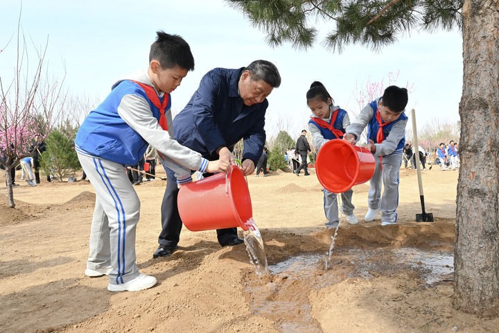 4月3日，党和国家领导人习近平、李强、赵乐际、王沪宁、蔡奇、丁薛祥、李希、韩正等来到北京市丰台区永定河畔参加首都义务植树活动。这是习近平同少先队员一起给刚栽下的树苗浇水。新华社记者 谢环驰 摄